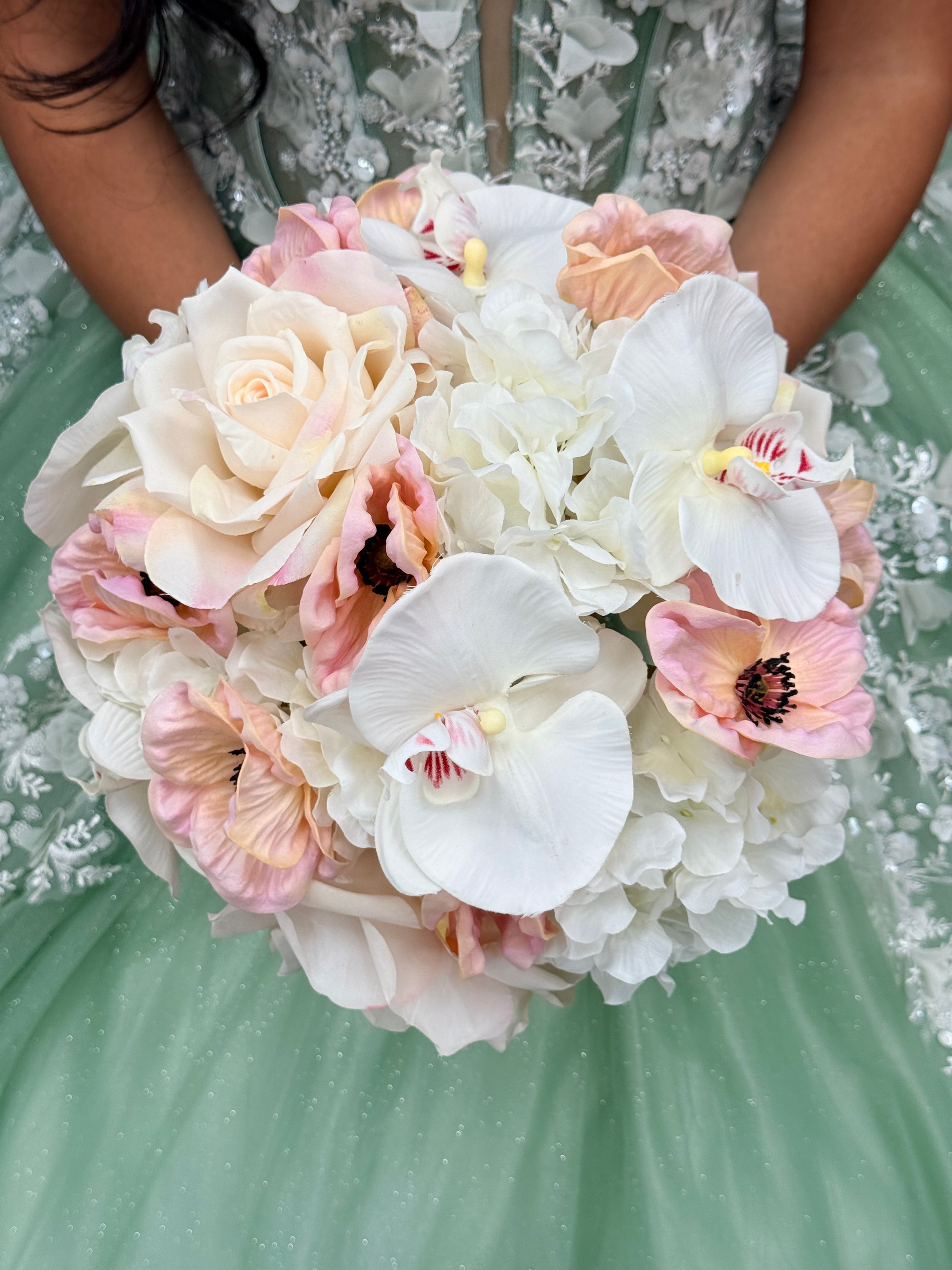 Quinceañera bouquet with white orchids, blush roses, and hydrangeas against a mint gown