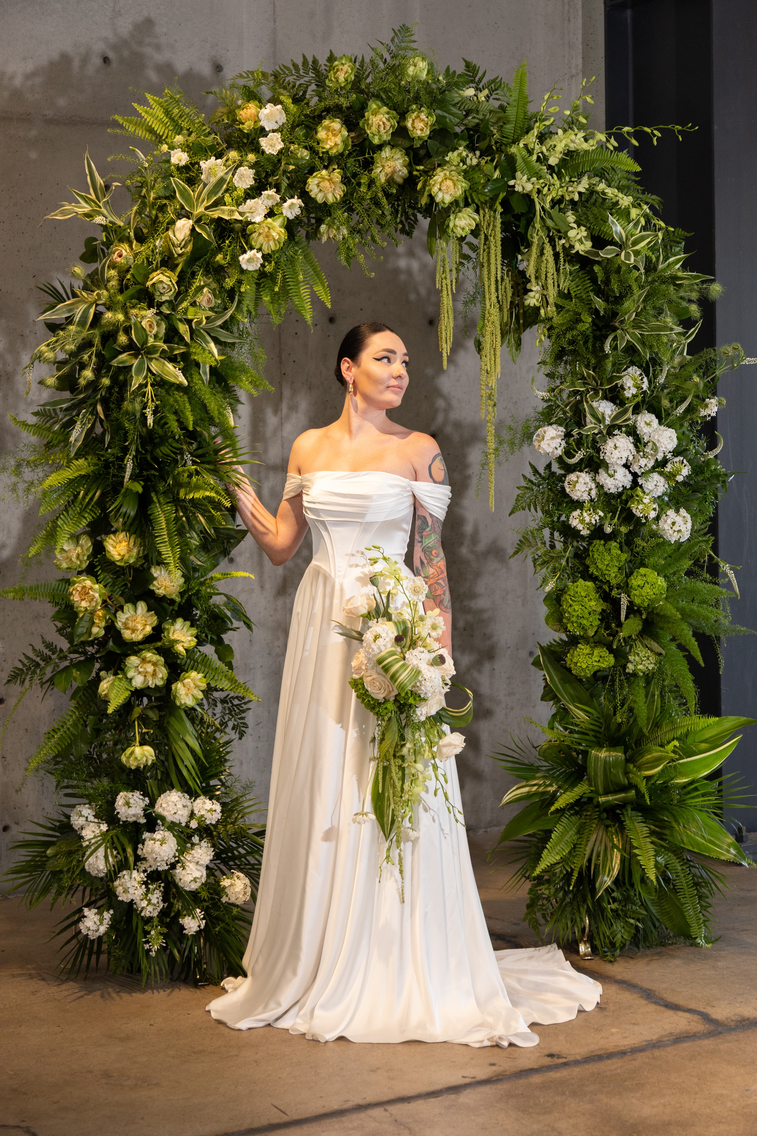Bride with colorful rainbow floral arch in purples, oranges, and yellows