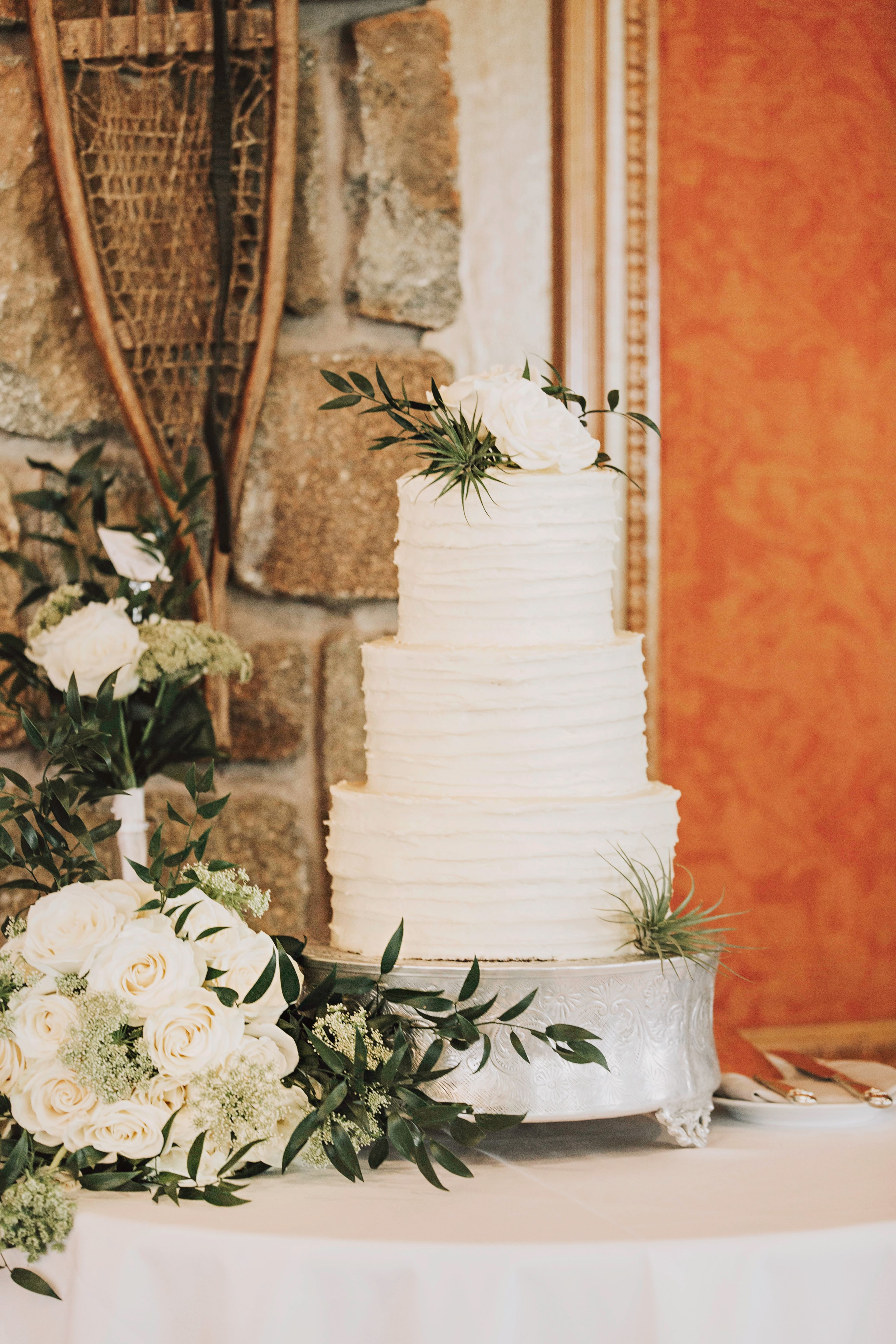 Three-tier white wedding cake with white roses and greenery